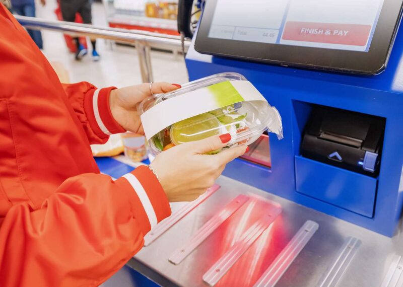 customer scans their own items at the self-service checkout in a convenience store