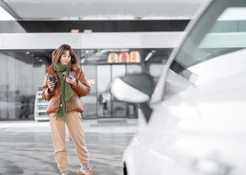 woman on mobile device standing in front of convenience store