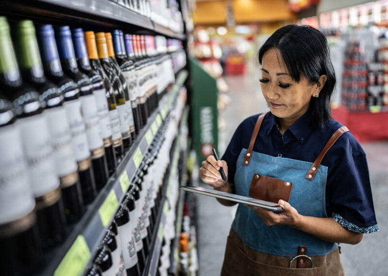 Woman taking inventory of alcohol and beer in a convenience store
