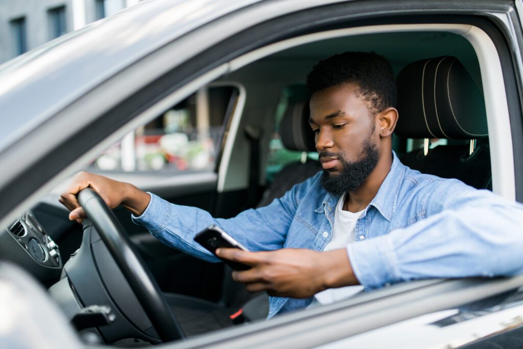 Young man using consumer application to find gas station while in car.
