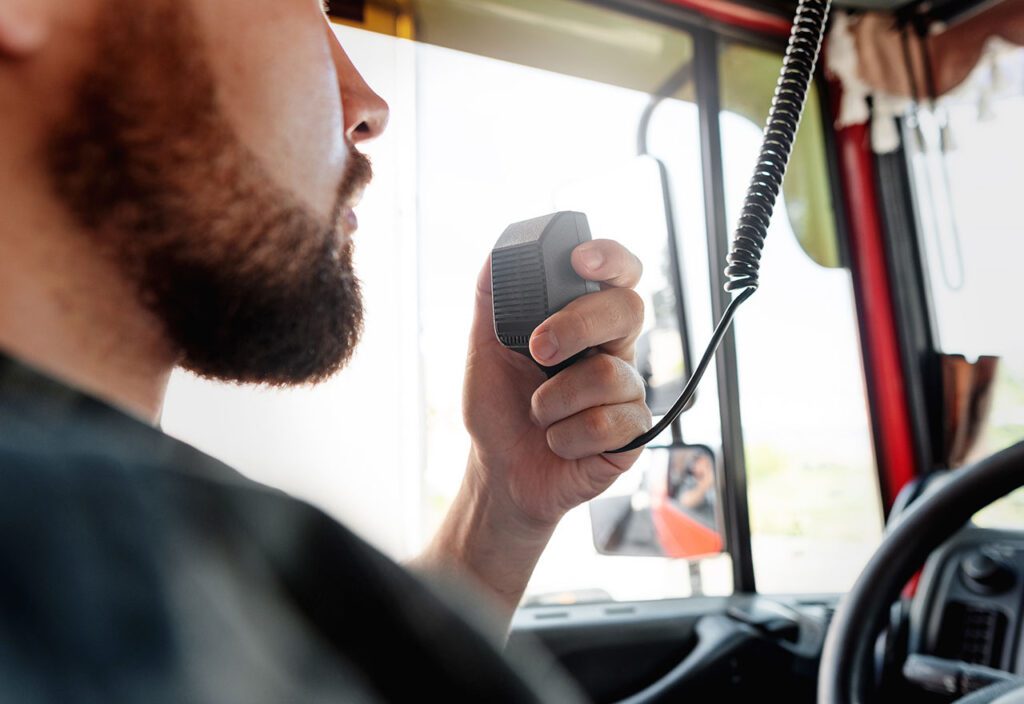 Truck driver using CB radio inside cab of his semi-truck.