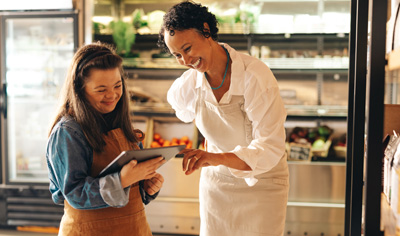 Two women looking at mobile tablet in convenience store