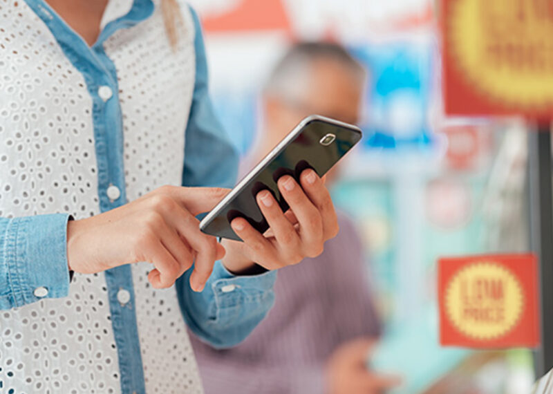 Consumer using a mobile phone in the CPG store