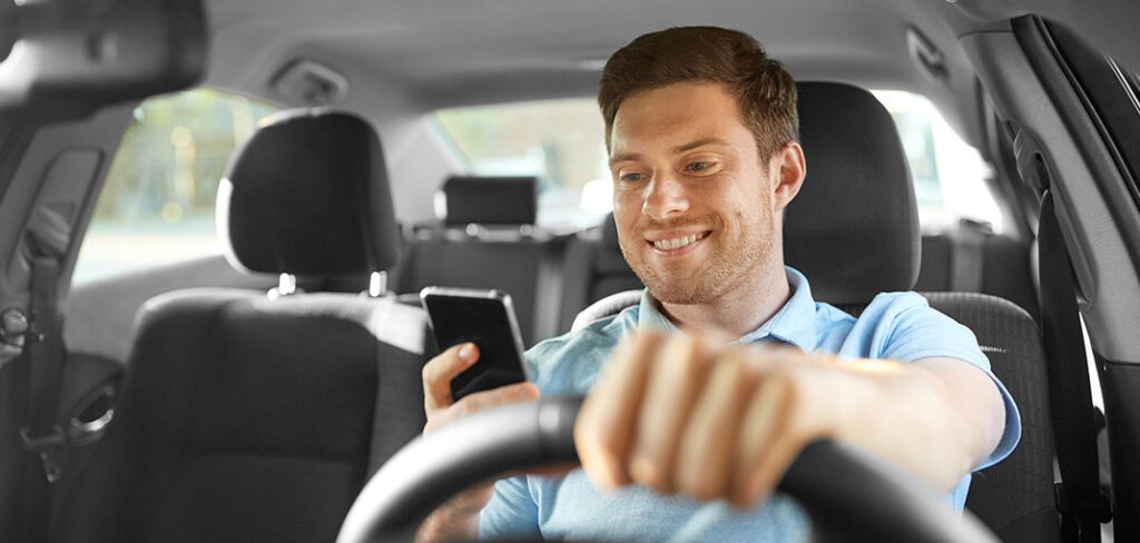 smiling man or driver driving car and using smartphone