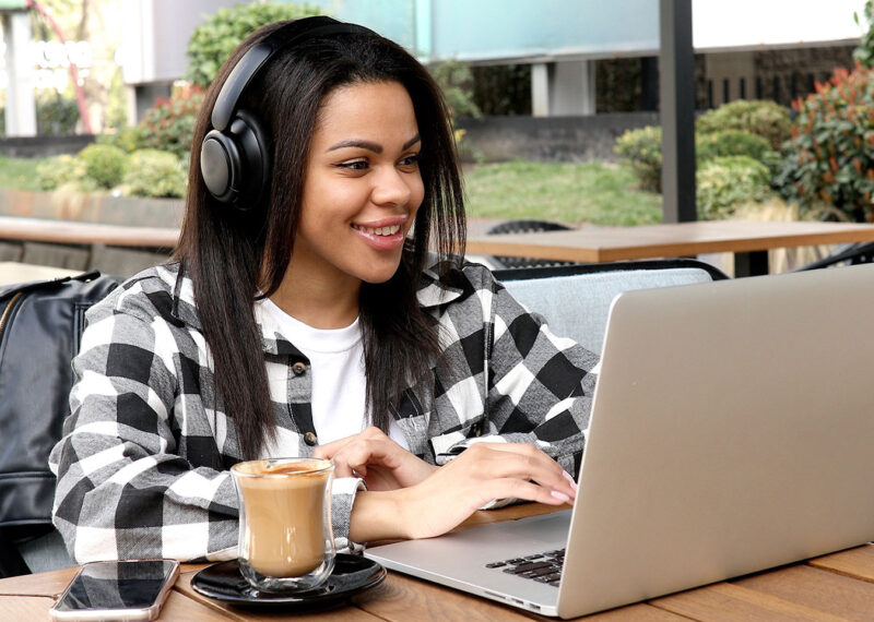Woman wearing headphones and working on laptop while sitting at restaurant using their secure Wi-Fi