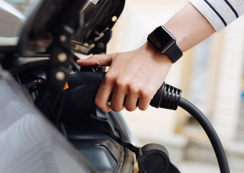 Female hand holding charger for electric vehicle