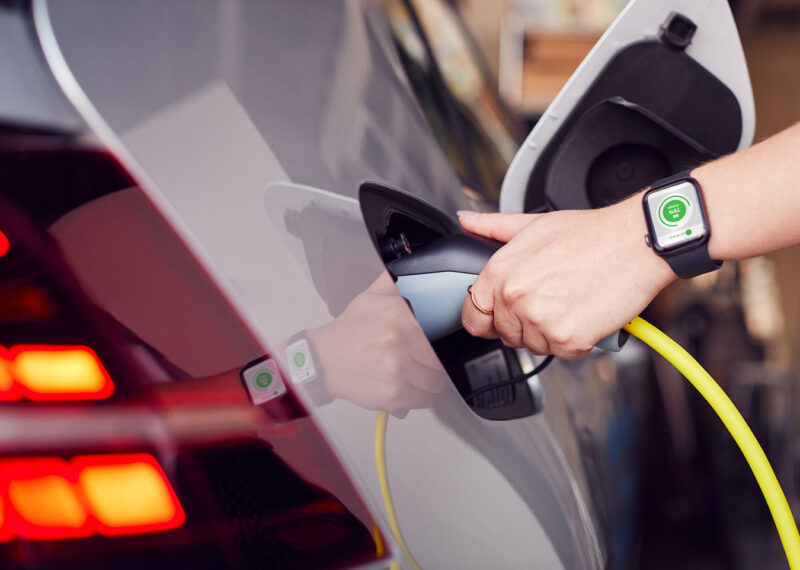 Close Up Of Hand Attaching Power Cable To Environmentally Friendly Zero Emission Electric Car