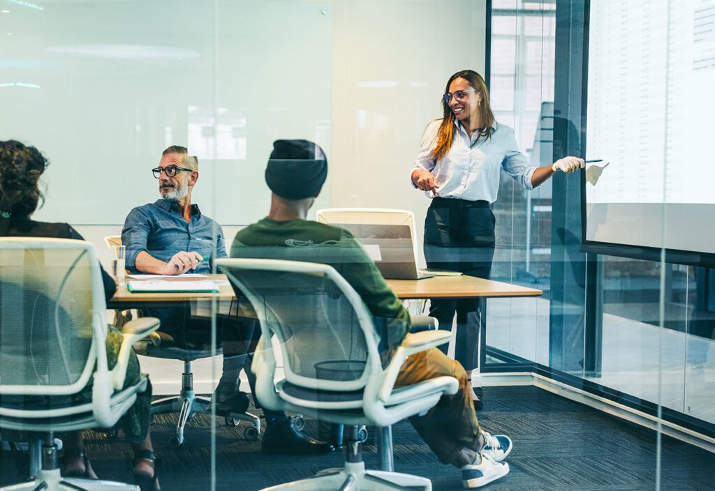 Female employee presenting financial data to colleagues in technology-driven office.