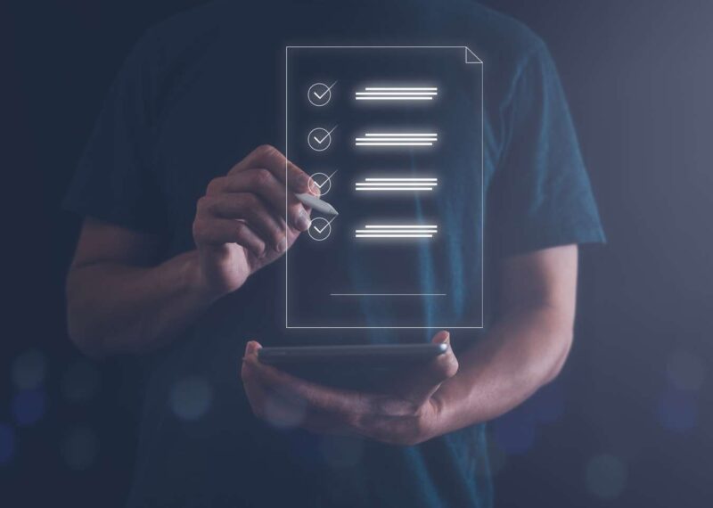 Person standing holding tablet and drawing a checklist with a stylus