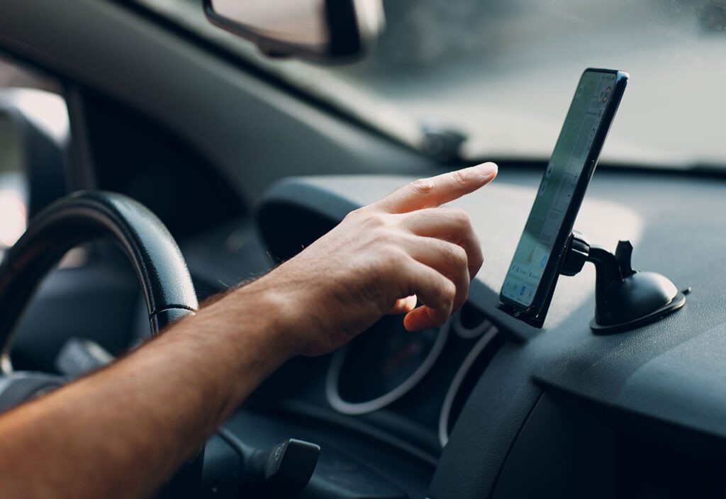 Close up of driver's hand using app on mobile cell phone for GPS navigation to nearest gas station.