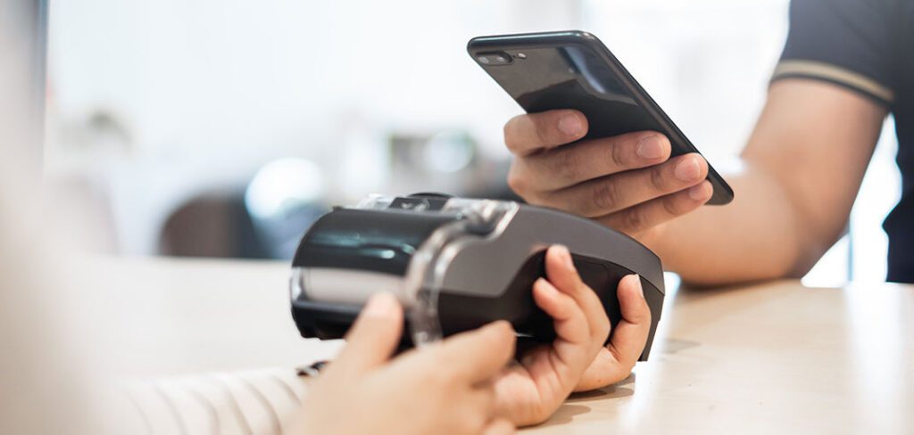 Woman paying at merchant terminal using debit or credit card with chip.