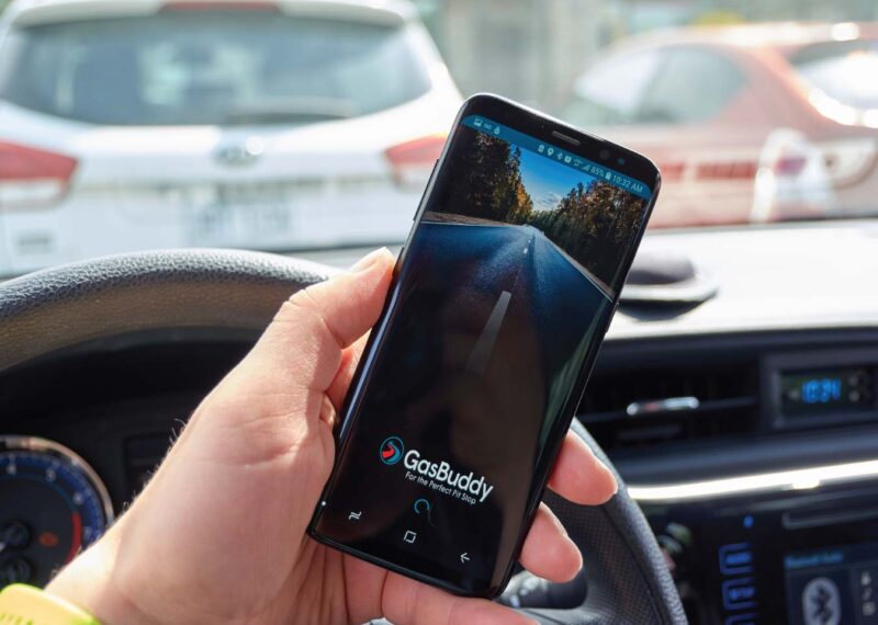 Man in a car using GasBuddy app