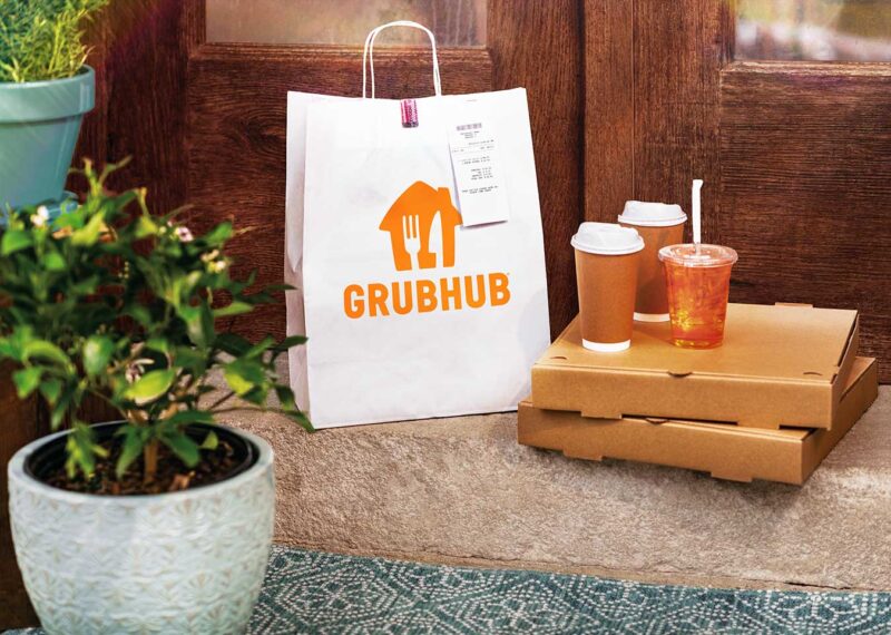 Grubhub bag on bench next to cardboard food boxes and drinks, food delivery loyalty