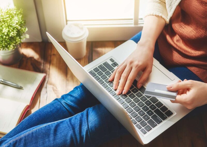 Person sitting with laptop and holding credit card while typing