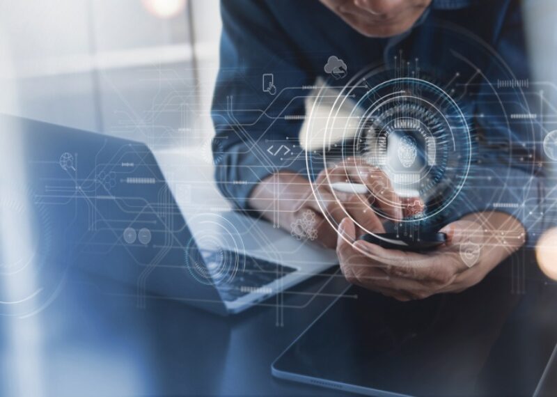 A person with a laptop using a cell phone