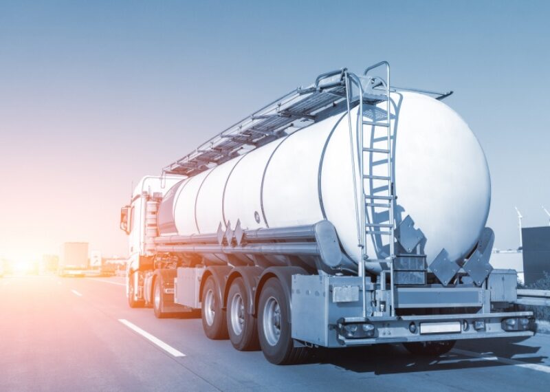 A fuel truck driving towards a sunset
