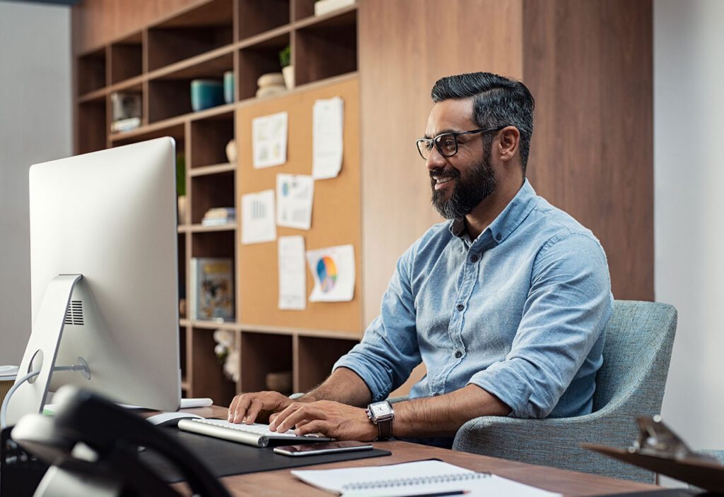 Operations manager working on desktop computer in office.