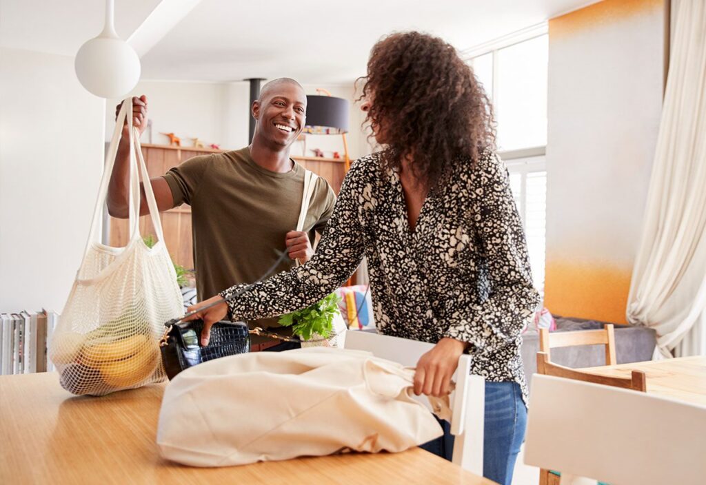 Couple unpacking consumer goods from reusable grocery bags.