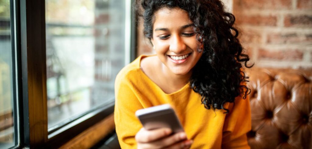 Woman holding phone smiling in living room