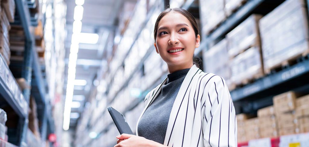 Business owner using  tablet to checking stock product inventory on shelf at distribution warehouse.