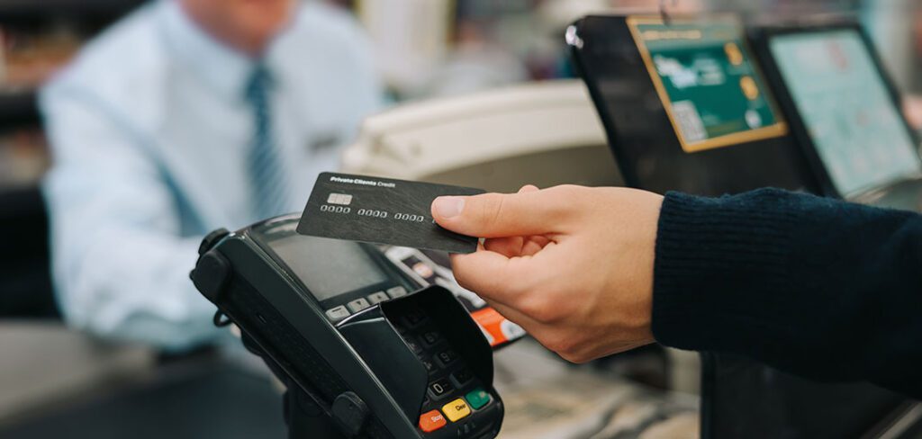 Customer at consumer packaged goods store using tap to pay at merchant terminal.