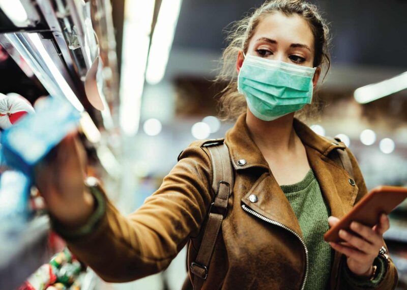 Mask-wearing woman purchasing items in store