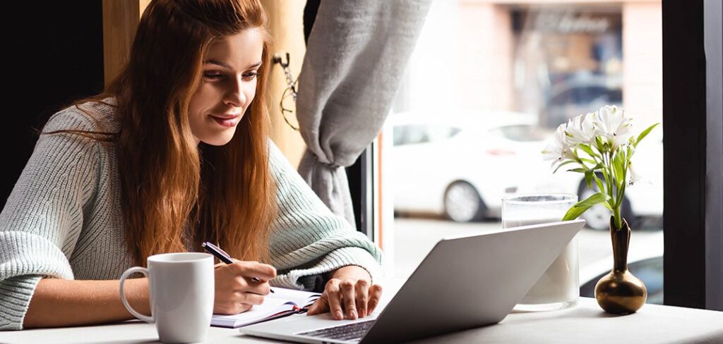 Woman sitting in cafe working on laptop.