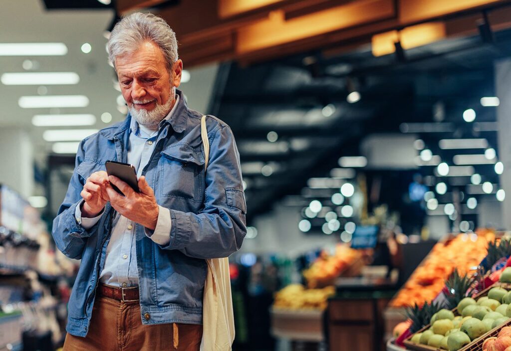 Male customer using phone while shopping at consumer packaged goods retail store.