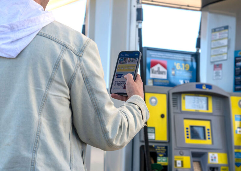 Man using loyalty app on smartphone at fuel pump