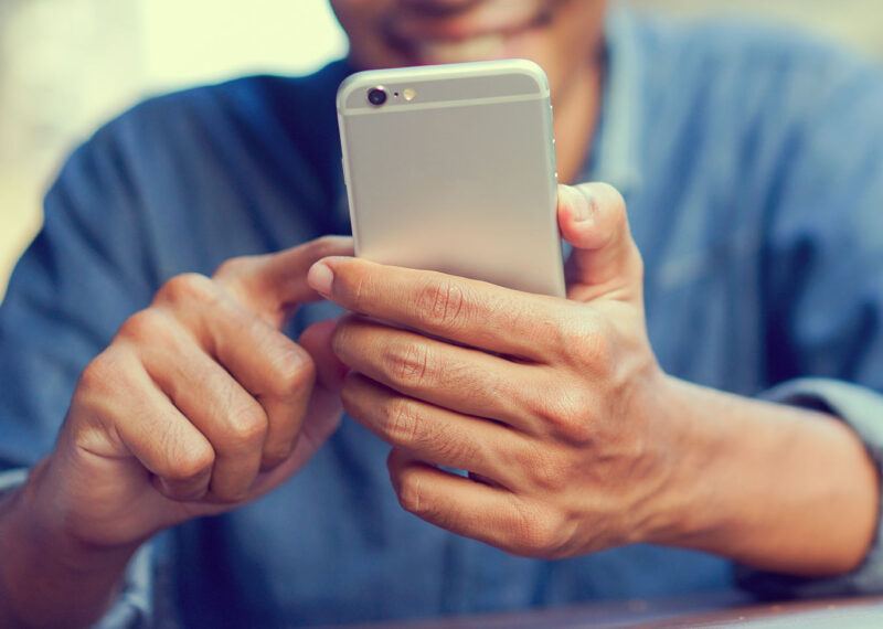 Man holding mobile phone and tapping screen
