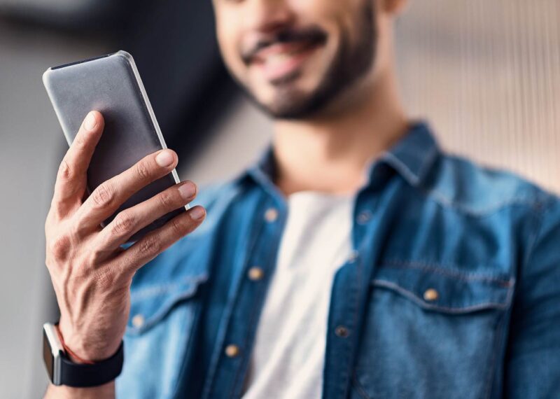 Man smiling while using his mobile phone