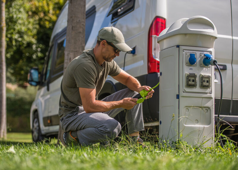 Man Attaching Electric Plug to RV Park Hookup