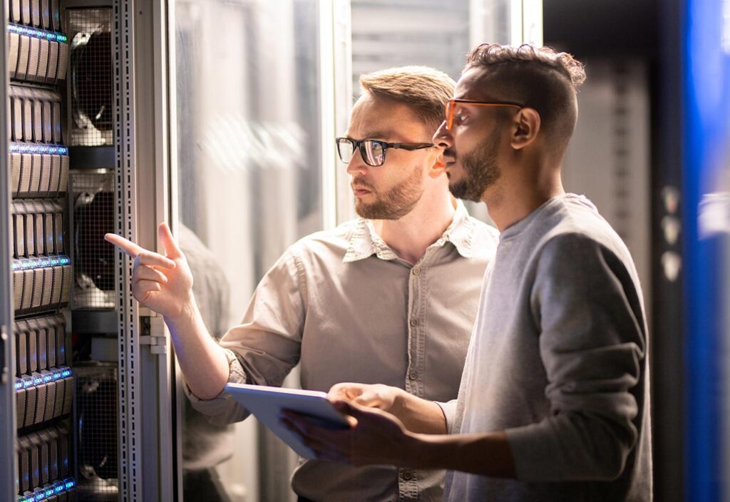 Young businessman talking on phone and using a laptop during a late night at work. 