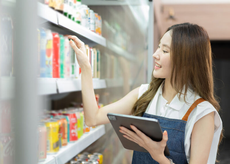 Woman at drink fridge in store looking at products