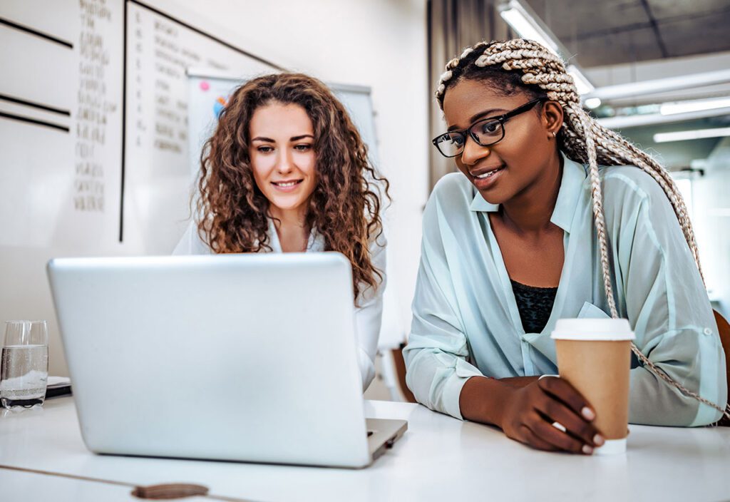 Two female coworkers engaged in collaboration on laptop.