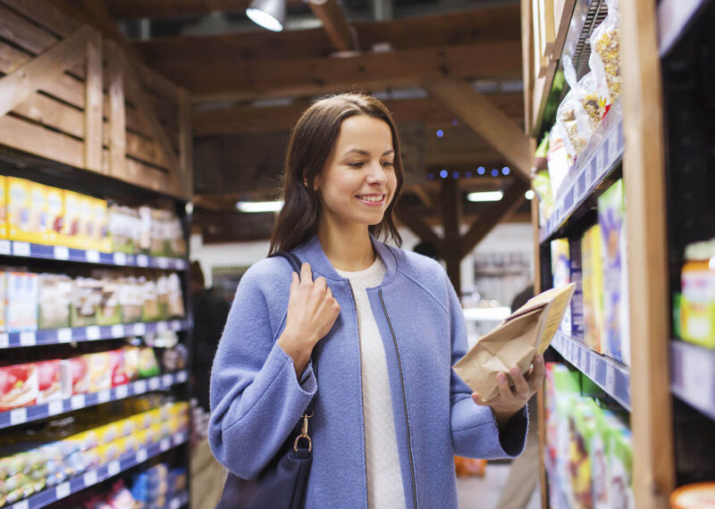 Woman in grocery store aisle looking at a product