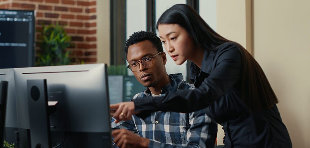 Programmers team discussing algorithms looking at monitors with code 