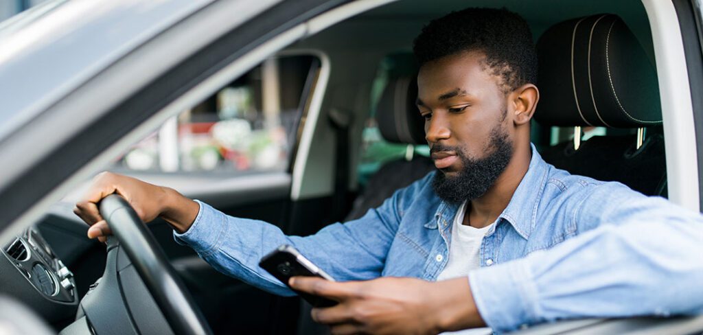 Young man using consumer application to find gas station while in car.