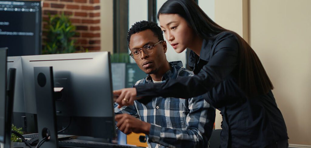 Two software developers coding network security interface and pointing at computer screen.