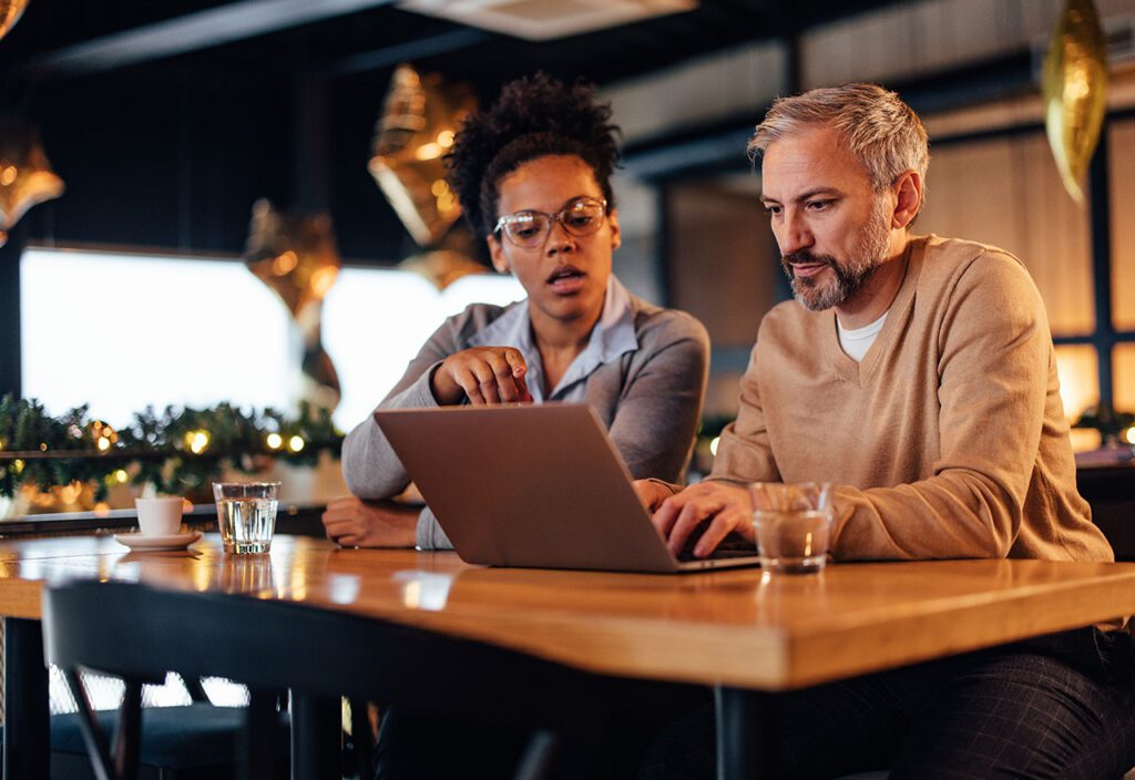 Cybersecurity tech man helping businesswoman remove malware from her laptop.