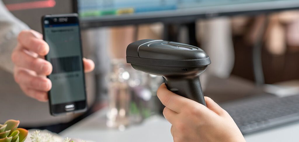 Female cashier scanning QR code on cell phone from customer using barcode scanner with POS in background.