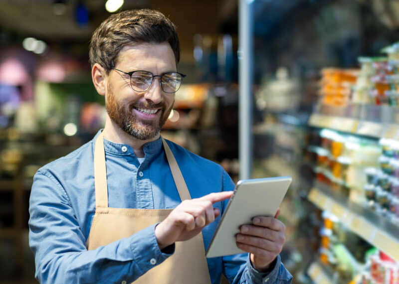 Convenience store employee using tablet technology to manage staffing and training, representing modern workforce solutions from PDI’s C-Store Workforce Guide.