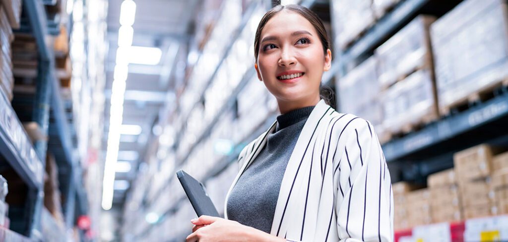 Female business owner using tablet to manage logistics and warehouse inventory.