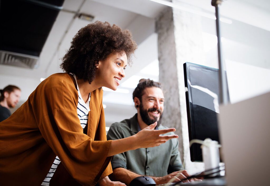 Woman leaning over programmer working in software development company.
