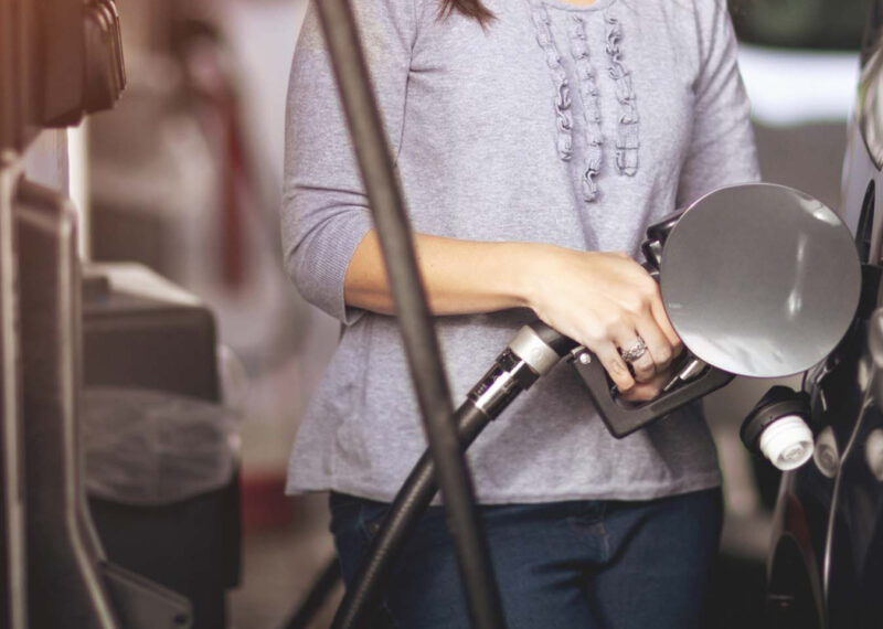 Woman pumping gas into vehicle at fuel pump