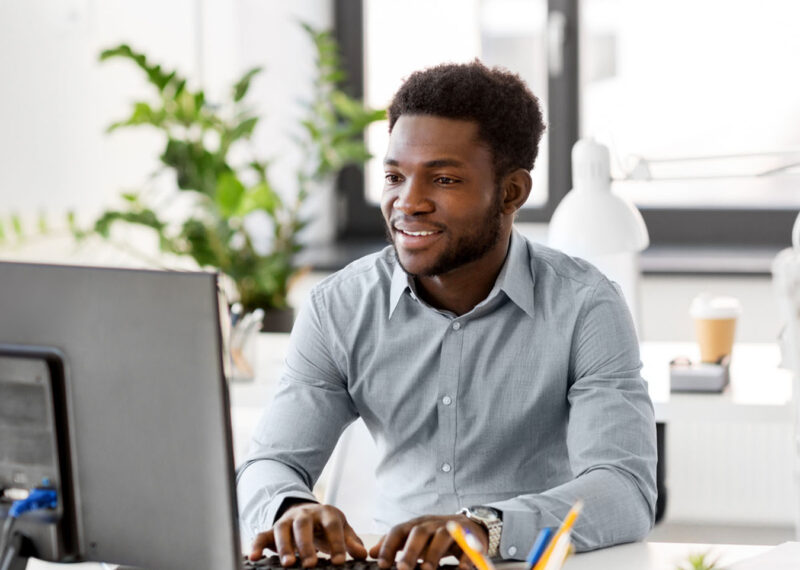 man working on computer with smile at his workplace