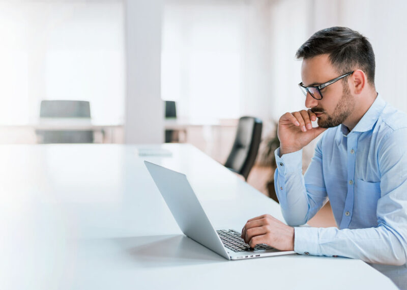 Man in business attire thinking about the project while looking at laptop