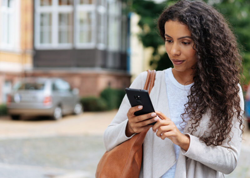 Female employee walking to transparent workplace on phone